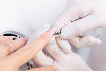 Obraz na płótnie Canvas manicurist uses cuticle scissors to process a client's manicure in a beauty salon