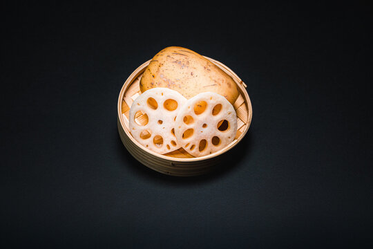 Fresh lotus root, close-up in bamboo bowl on black background