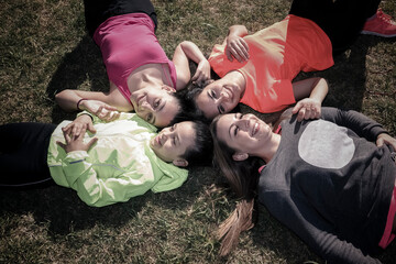 Fotografía cenital de cuatro mujeres de distintas edades tumbadas boca arriba en la hierva...