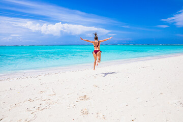 Fototapeta na wymiar A cheerful girl jumps up on a paradise beach in the Maldives