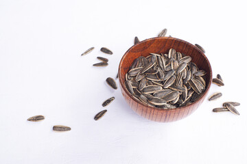 Sunflower seeds in a wooden bowl on a white table