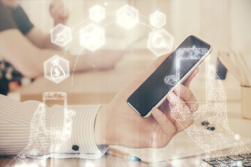 Double exposure of man's hands holding and using a digital device and tech theme hologram drawing. Technology concept.