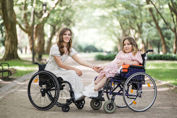 Obraz premium Charming caucasian women that lives with chronic health condition enjoying summer weather at green park. Two friends wearing stylish dresses with floral print. Support and understanding concept.