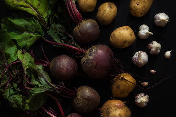 Set of vegetables on a black background. Beets, potatoes, onions and garlic.
