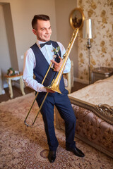 Young groom professional trumpeter holding a trumpet in his hands.