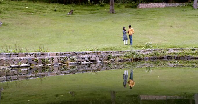 A young adult Indian man taking a picture of his girlfriend in a park shot in 4K