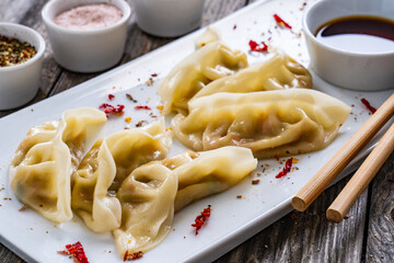 Gyoza - delicious dumplings filled with vegetables, wrapped into thin dough served with soy sauce on wooden table
