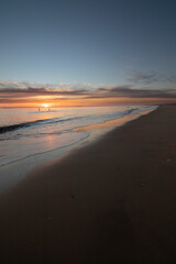 A beautiful sunset on the beach of Mazagon, Spain. In the background the silhouettes of two surfers.