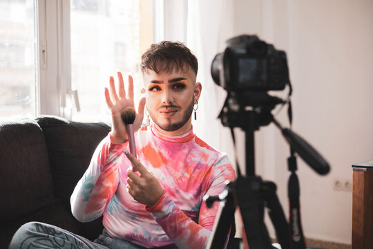 Gay Man Showing Makeup Brush On Social Media Live Video Feed With Video Camera. Lifestyle And Fashion Concept.