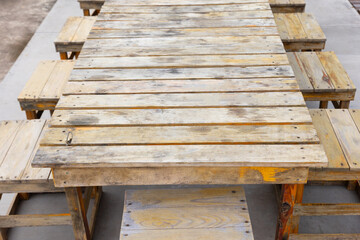 Front view of old, vintage and grunge wooden table including chairs with beautiful surface texture of weathered materials. It can be used for outdoor abstract background for people meeting and party.