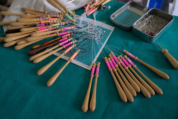 Lacemaker work in progress, close-up. Table, bobbins and thread.