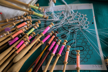 Lacemaker work in progress, close-up. Table, bobbins and thread.