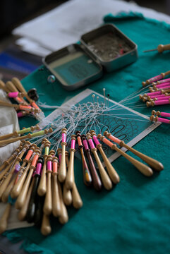 Lacemaker work in progress, close-up. Table, bobbins and thread.