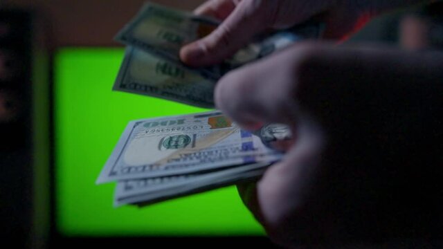 Hands of a man counting out a wad of dollar bills