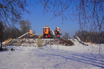 Naklejka premium Children's playground in a winter setting. Children's playground in a winter scenery. Family outdoors on a frosty sunny day 