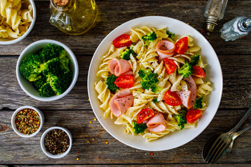 Pasta with ham, broccoli and cherry tomatoes  on wooden table