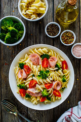 Pasta with ham, broccoli and cherry tomatoes  on wooden table