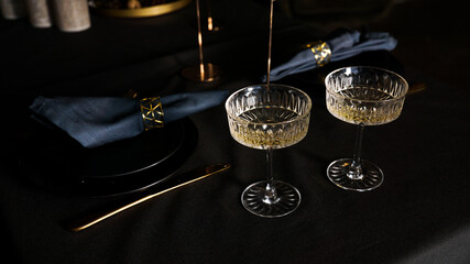 Two popular vintage champagne glasses on a dark background of the lux served table. Festive dinner...