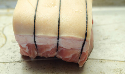 Boneless pork loin joint tied with string on the oven tray, raw meat prepared for baking