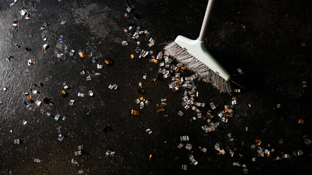 Cleaning broom and golden confetti on a black background. The concept of cleaning after the holiday, cleaning, professional cleaning. Top view.