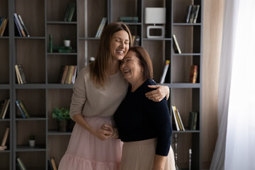 Warm relationship. Loving grownup child daughter and mature mother retiree hugging laughing holding...