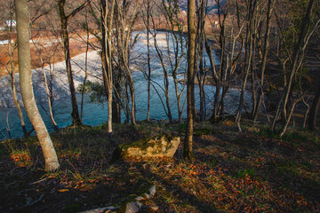A mountain river in the middle of the forest in late autumn. An atmospheric landscape with a mountain river and an autumn forest. A river valley among mountain hills on an autumn day.