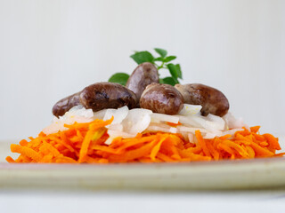 Chicken hearts, carrot and onion fresh tasty salad on white plate on wooden table. Side view