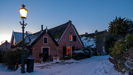 Snowy old traditional dutch houses in the countryside from the Netherlands in winter