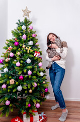 Happy smiling woman with domestic cat near the christmas tree
