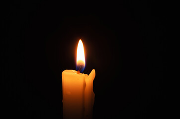 Burning candle in total darkness
