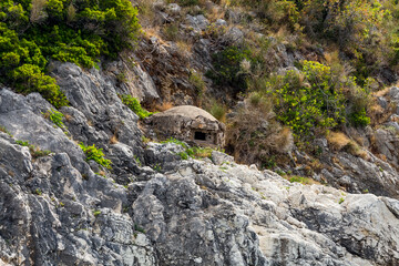 Military concrete bunker or pillbox in southern Albania built by communist government of Enver Hoxha on the shore of the Ionian Sea near Saranda town placed on the rock. Bunker is turned to the west.