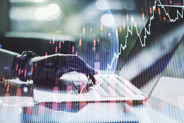 Abstract creative financial graph with world map and with hands typing on laptop on background, forex and investment concept. Multiexposure