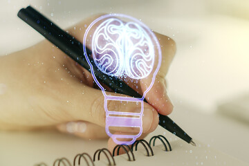 Creative idea concept with light bulb and human brain illustration with man hand writing in...
