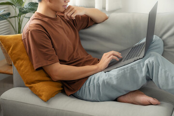 Work at home young asian man working on laptop computer while sitting at home Morning lifestyle