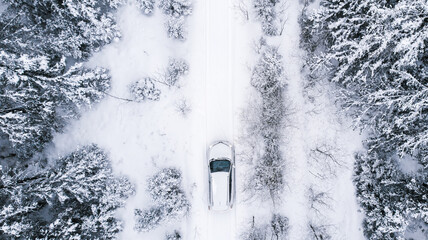 Natural background. A winter snow-covered road in the forest and a car that goes on a journey.