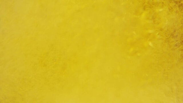 Bubbling Beer, Liquid then Whoosh of Fizz (ideal transition). The lager drink then settles and bubbles. Full screen, close up. Natural Carbonated Drink Yellow Background.