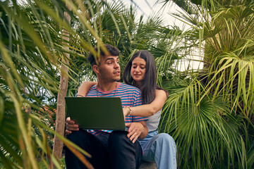 young couple looking a laptop and talking with her friends