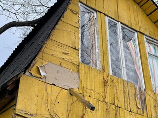 Old yellow wooden house in countryside. Building exterior of shabby unkempt rustic house. Close up.