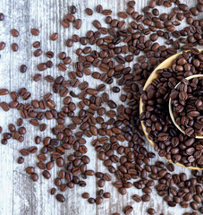 Half a cup filled with coffee beans surrounded by coffee beans. Cutting board, recipe, advertisement, catalog, menu, website, poster, postcard. Coffee beans close up. Dried and roasted coffee beans.