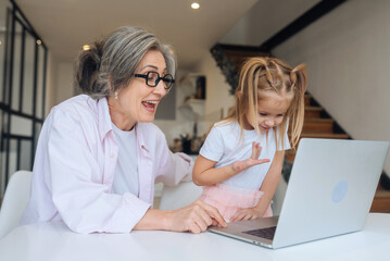 Child and granny looking at the camera with laptop