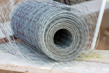 Rolled up silver construction mesh sitting on a wood surface