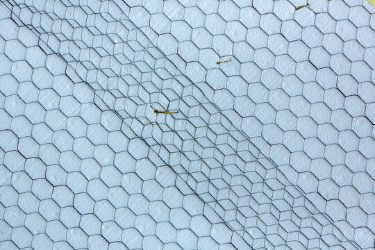 Overlapping panels of construction mesh over a white foam surface