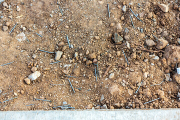 Framing nails scattered all over the ground next to a sidewalk