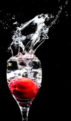 Peach water splash with a wine glass showing the sharp water splash and droplets on a black backdrop in a studio