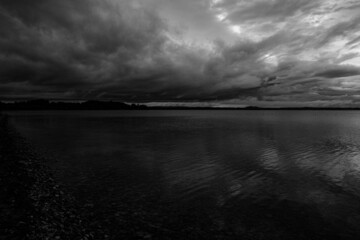 black and wite cloudscape with reflection in calm lake water, summer evening sunset light