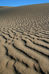Beautiful dune sand textures as wind blows the sand across with a beautiful blue sky