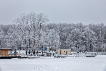 Boat station on a frozen pond in a city park surrounded by frosted trees