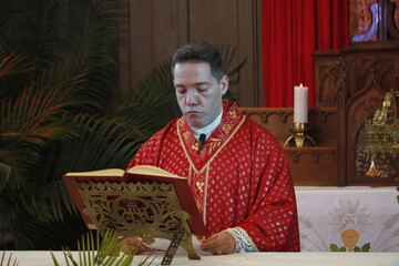 A priest celebrates a catholic mass dressed in a red chasuble 