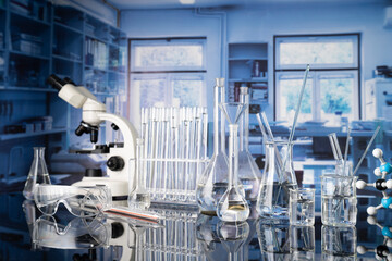 Laboratory investigations concerning test and medicine against covid. Microscope, glass tubes and beakers on blue background.