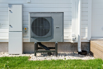 Air source heat pump installed on the exterior of a modern wooden house. Air source heat pump...